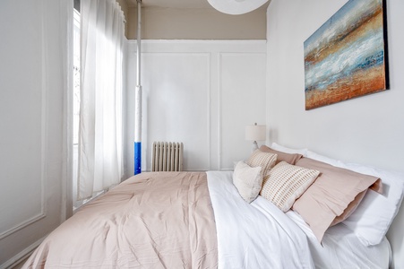 Slip into this serene bedroom where soft blush linens and natural light create your perfect retreat for restful nights.