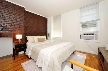 Your cozy bedroom features exposed brick charm, crisp linens, and modern comfort with AC to ensure restful nights.