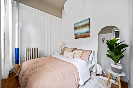 Your peaceful bedroom sanctuary features soft blush bedding and thoughtful touches like fresh greenery for ultimate relaxation.