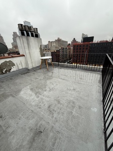 Step onto your private rooftop terrace with sweeping city views and urban skyline stretching beyond black railings.