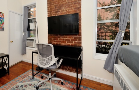 Your cozy workspace features exposed brick, a sleek desk, and large windows overlooking leafy streets for productive mornings.
