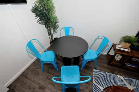 Gather around your stylish dining table, surrounded by vibrant blue chairs and lush greenery that creates the perfect atmosphere for memorable meals.