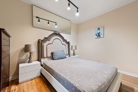 Settle into your stylish bedroom with elegant track lighting, ornate headboard, and modern touches creating the perfect retreat.