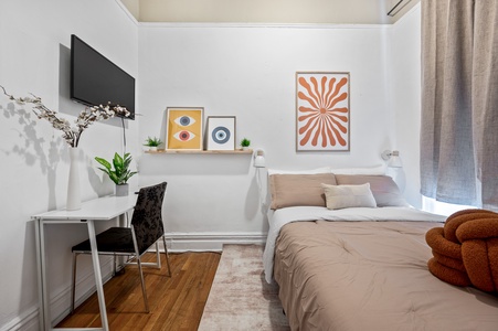 Your cozy bedroom features modern artwork, a workspace, and warm natural light for productive relaxation.