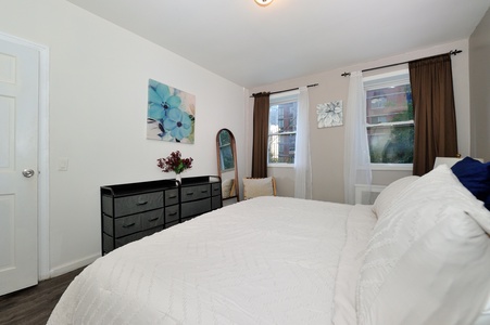 Sink into this cozy bedroom's plush white bedding and wake up to natural light streaming through your windows.