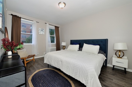 Sink into crisp white linens in your peaceful bedroom, where warm natural light flows through large windows.