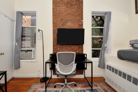 Work comfortably at your dedicated desk space with exposed brick charm and city views from both windows.