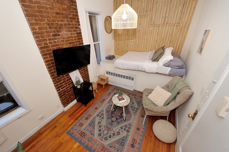 Your cozy studio blends rustic brick walls with modern comfort, featuring a plush bed, smart TV, and stylish seating area.