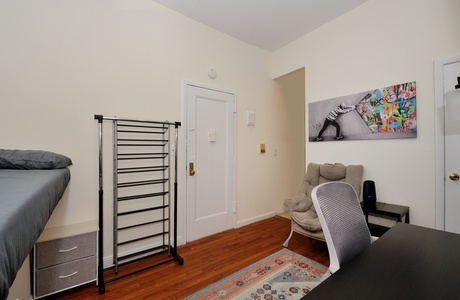 Relax in your cozy bedroom with vibrant artwork, comfortable seating, and thoughtful storage solutions for a perfect stay.