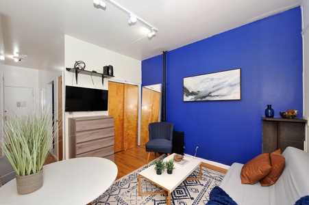Relax in your vibrant living space featuring a striking blue accent wall, cozy seating, and modern amenities for your perfect stay.