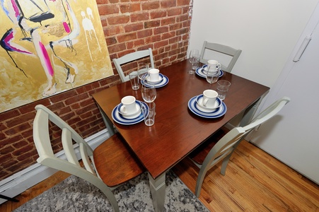 Your dining space combines urban charm with warm comfort—exposed brick walls and colorful artwork create the perfect backdrop for memorable meals.