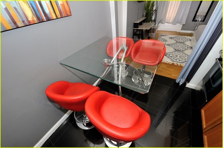 Gather around this sleek glass dining table with vibrant red chairs for memorable meals and conversations in your stylish retreat.