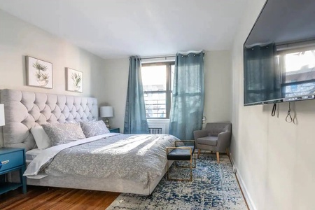 Your serene bedroom features a plush tufted headboard and calming blue accents, creating the perfect retreat for peaceful nights.