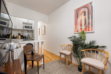 Settle into your stylish open-plan space where modern kitchen meets cozy living area with warm wood floors and chic furnishings.