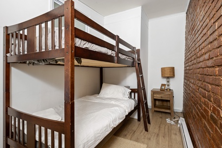 Cozy bunk bed room with exposed brick walls creates your perfect family retreat with rustic charm and modern comfort.