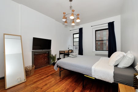 Your stylish bedroom features crisp white linens, warm hardwood floors, and a charming brick fireplace that creates the perfect retreat.