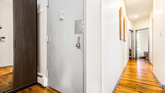 Step into your private entrance hallway, where gleaming hardwood floors guide you toward bright, welcoming bedrooms and modern living spaces.