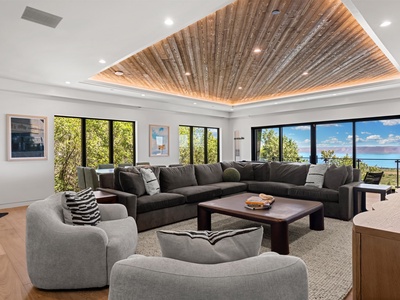 Sink into plush seating beneath a stunning reclaimed wood ceiling while panoramic windows frame lush greenery and stunning water views—your perfect retreat for gathering with loved ones.