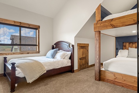Rest easy in your thoughtfully designed bedroom, where a handsome wooden bed and cozy bunk nook offer comfort for the whole family beneath vaulted ceilings and warm natural light.
