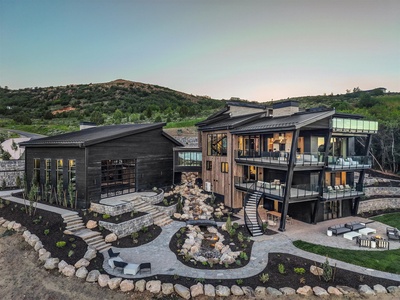 Striking modern architecture nestled into hillside terrain with multiple outdoor living spaces and scenic mountain views—a spectacular backdrop for arrival.