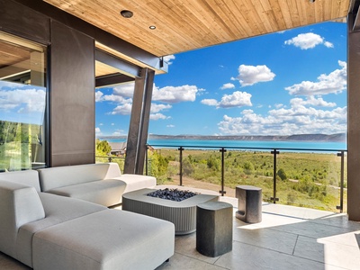 Relax on your private terrace with plush seating and a modern fire feature while soaking in stunning lake and mountain views under soaring wood ceilings.
