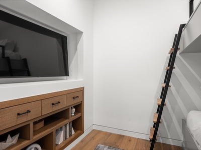 Bright minimalist room with modern TV console and ladder access to your loft—perfect for a cozy, space-saving retreat.