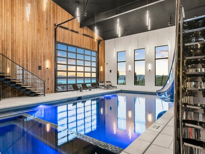 Dive into your private oasis where modern design meets lakeside serenity. Glide down the waterslide or lounge poolside beneath soaring ceilings, as golden-hour light dances through floor-to-ceiling windows framing breathtaking water views.