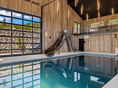 Your private indoor pool paradise awaits—soaring ceilings, a sleek water slide, and natural light pouring through expansive windows create an unforgettable retreat for year-round fun.