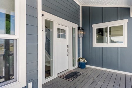 Modern cottage entrance with covered porch and charming blue siding welcomes you home.