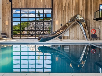 Dive into fun at your private indoor pool, complete with a sleek stainless slide that promises endless entertainment for all ages in this stunning modern space.