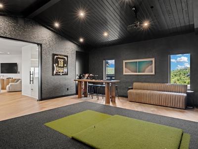Your own private game room awaits with a putting green, stylish lounge seating, and a bar setup—perfect for unwinding after a day exploring nearby attractions.