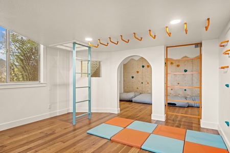 A whimsical indoor play space with climbing walls, monkey bars, and soft mats invites your little adventurers to explore and burn energy no matter the weather.