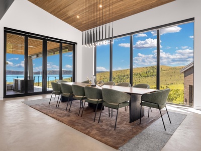 The stunning lakefront dining room showcases panoramic windows that fill your space with natural light while you enjoy sweeping lake and mountain views, making every meal feel effortlessly special.