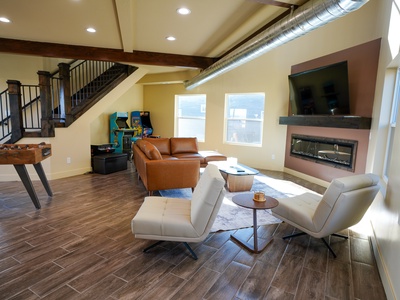 Unwind in your spacious living area with modern furnishings, a cozy fireplace, and entertainment options including arcade games.