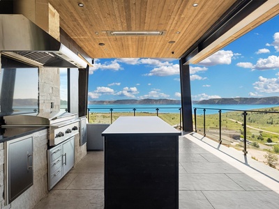 Your private outdoor kitchen opens to breathtaking lake and mountain panoramas. Fire up the grill, gather around the island, and savor meals beneath soaring wood ceilings with nature as your backdrop.