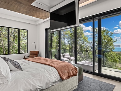Wake in this serene bedroom where floor-to-ceiling windows frame lush treetops and sparkling lake views, while your private balcony invites morning coffee in the fresh air.