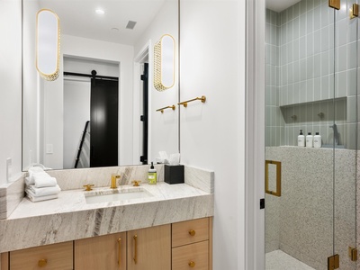You'll love starting your day in this luxurious spa-style bathroom with elegant gold finishes, plush towels, and a sleek walk-in shower—pure relaxation awaits.