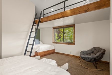 Your cozy retreat features stylish bunk beds and a relaxing lounge chair—perfect for families or groups seeking comfort and connection in a warm, thoughtfully designed space.