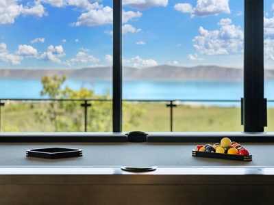 Challenge a friend to a game of pool while soaking in stunning turquoise lake views framed by distant mountains and endless blue skies.