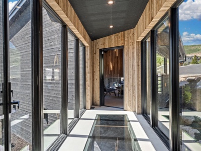 Step into your private glass-floored bridge connecting the property, where natural light floods this architectural walkway and mountain views surround you on every side.