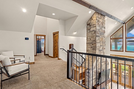 Soaring ceilings and a stunning stone fireplace create a dramatic yet inviting space where you can unwind with breathtaking lake views through expansive windows.