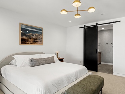 Sink into the plush bedding and unwind beneath the modern chandelier, while the stylish barn door reveals your private ensuite bathroom just steps away.