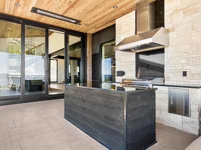This stunning outdoor kitchen boasts a sleek built-in grill and prep station under a beautiful wood-plank ceiling, perfect for your al fresco dining experiences. Seamless indoor-outdoor flow makes entertaining effortless.