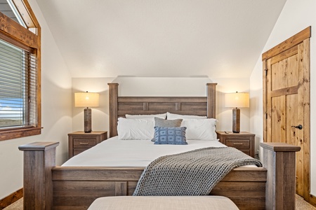 Sink into plush linens and rustic charm in your serene bedroom retreat, where warm wood tones and soft lighting create the perfect space to unwind after a day of mountain adventure.