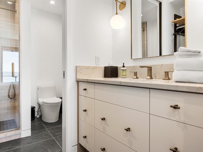 Your bright, modern bathroom features a stylish double vanity with marble countertops, chic brass fixtures, and plush towels stacked for your comfort.