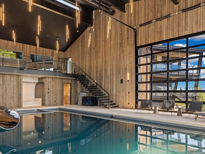 Soaring wood-paneled walls and dramatic lighting frame your private indoor pool, blending natural warmth with modern luxury for unforgettable relaxation.