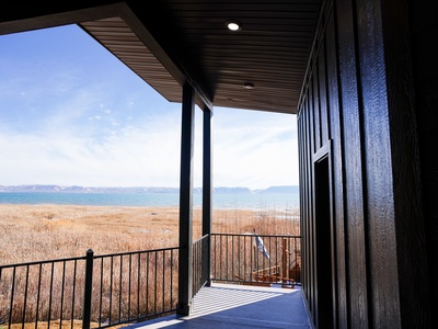 Modern covered terrace with breathtaking lake and mountain views across golden wetland scenery.