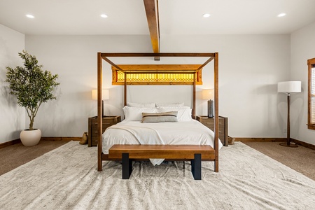 Sink into crisp linens beneath the striking canopy bed. Warm wood tones and soft lighting create your ideal sanctuary for a restful night.
