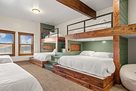 Your group will love this custom bunk room, where rustic wood beams and sage-green accents create a cozy mountain retreat. Plush white bedding and built-in steps make bedtime easy and fun.