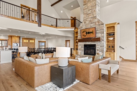 Gather around the stone fireplace in this stunning great room where soaring ceilings, warm wood accents, and plush seating create the perfect space for your group to relax together.